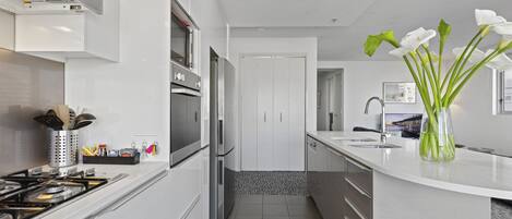 Una cocina moderna con armarios blancos, electrodomésticos de acero inoxidable y una isla central con un florero.