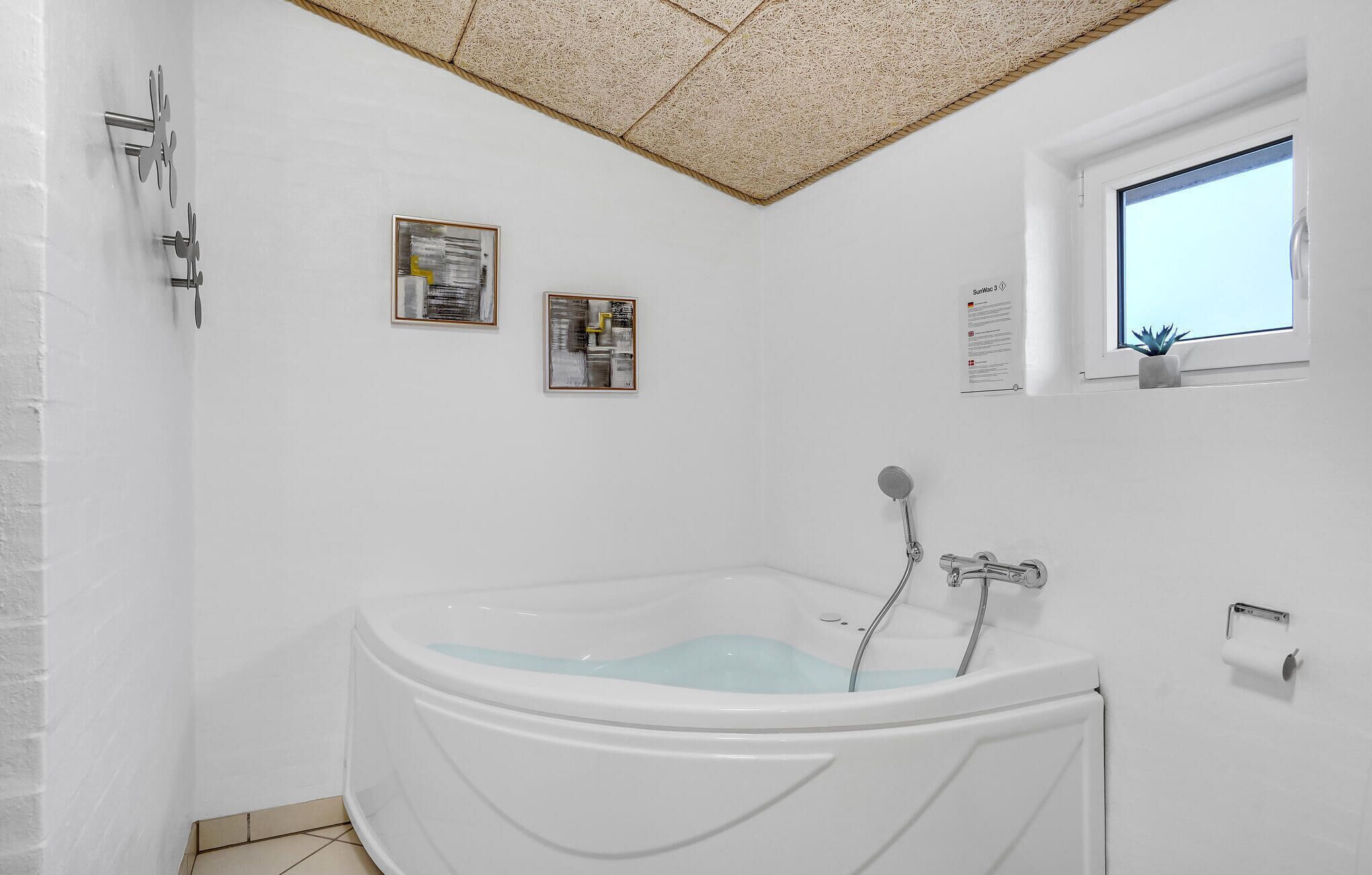 A modern bathroom with a freestanding bathtub, a showerhead, and two framed abstract paintings on the wall.