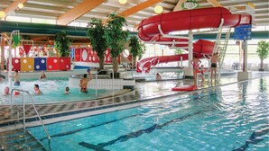 An indoor swimming pool with multiple lanes, a water slide, and a lifeguard stand. - 3 bedroom stunning home in Vlagtwedde (Vlagtwedde)