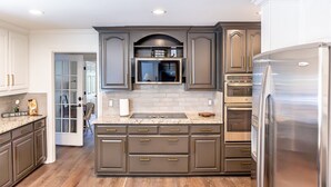Une cuisine moderne avec des meubles de couleur sombre, des appareils électroménagers en acier inoxydable et un plan de travail en marbre.