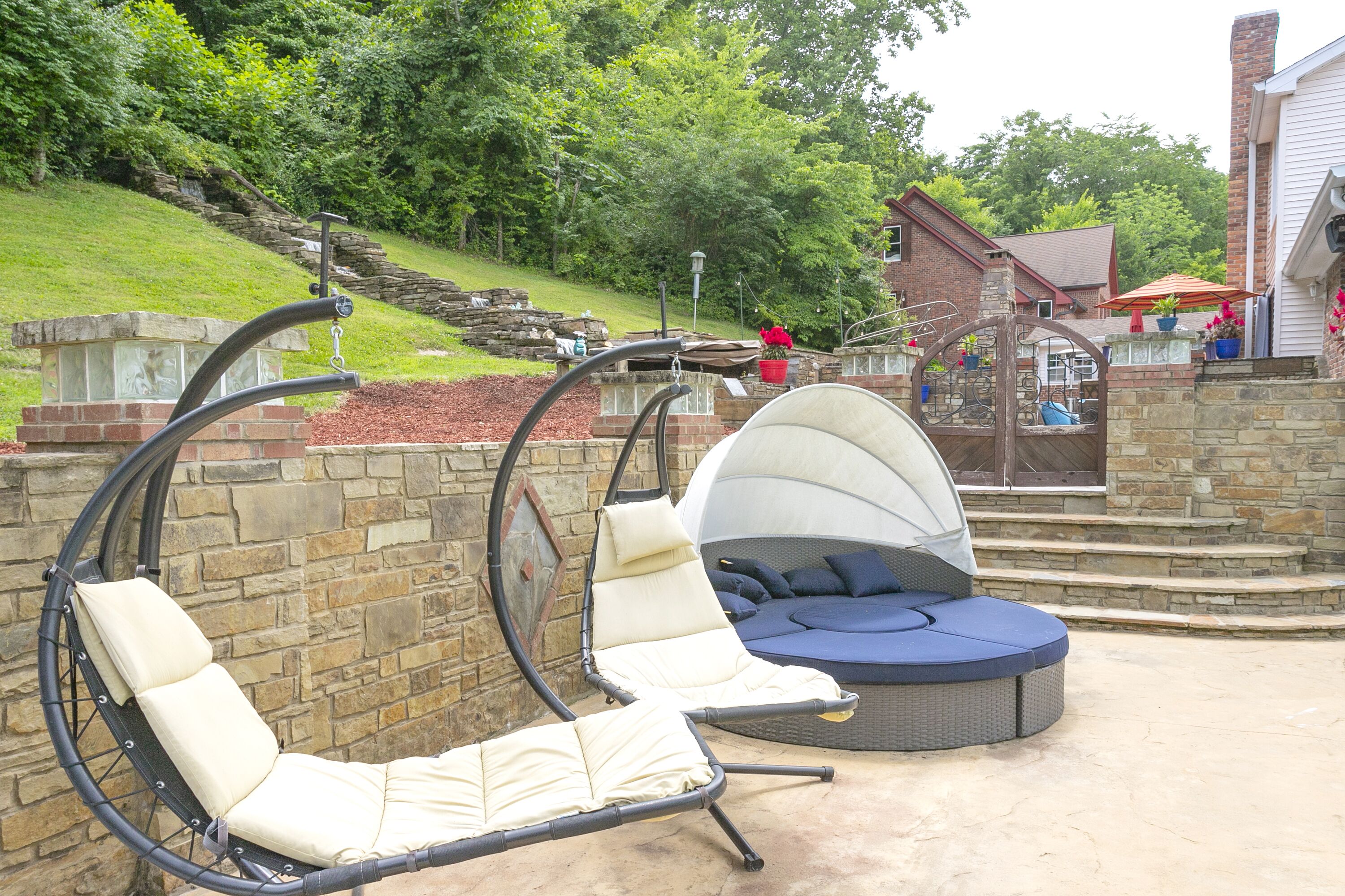 A patio area with two swing chairs and a round seating area.