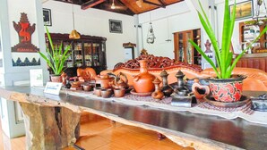A reception area with a wooden reception desk displaying various pottery items. - REVIVE Bogor Pendopo 45 Resort (Kemang)