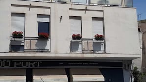 A building with three windows, each with a shutter and a flower box. The facade has a sign that reads "OFFICINA DEL GUSTO" and "DU PORT". - Holidayfever (Alghero)