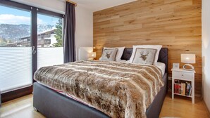 Un dormitorio con una cama grande, cabecera de madera, mesitas de noche y vistas al exterior.
