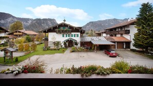 Un edificio de estilo chalé tradicional con techo inclinado, un coche estacionado al frente y montañas al fondo.