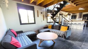 A modern living area with a sofa set, a round coffee table, and a staircase leading to a kitchen area.