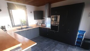 A modern kitchen with dark tiles, a wooden ceiling, and built-in appliances.