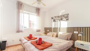 A modern hotel room with two beds, a large window, a ceiling fan, and a bedside table with a lamp. - Gorgeous apartment in Torrevieja (Torrevieja)