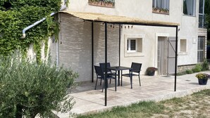 A covered outdoor seating area with a table and chairs, a pergola, and a potted plant. - Gîte Dipladenia with pool (Saint-Rémy-de-Provence)