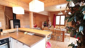 L’intérieur d’un chalet en bois comprend une cuisine, un coin repas et une cheminée.