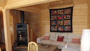 L’intérieur d’un chalet chaleureux, avec une cheminée, un canapé et une table à manger.