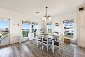 A bright, spacious room with a dining area, a kitchen, and large windows offering a view of the surrounding area.