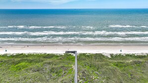 Une plage avec une longue jetée qui s’avance dans l’océan, un rivage sablonneux et une vue dégagée sur la mer.