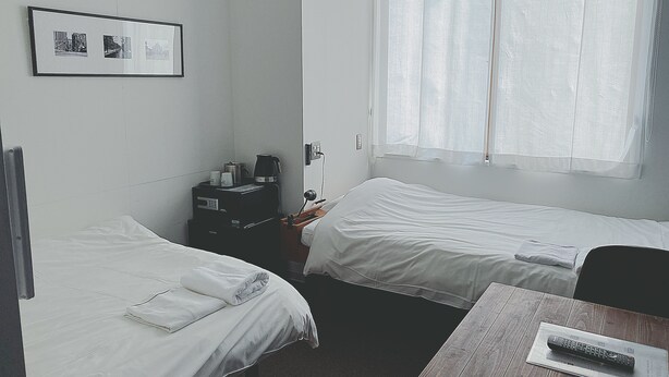 A hotel room with two beds, a small table, a coffee maker, and a framed photo on the wall. - fami THE GREEN OTARU (Otaru)