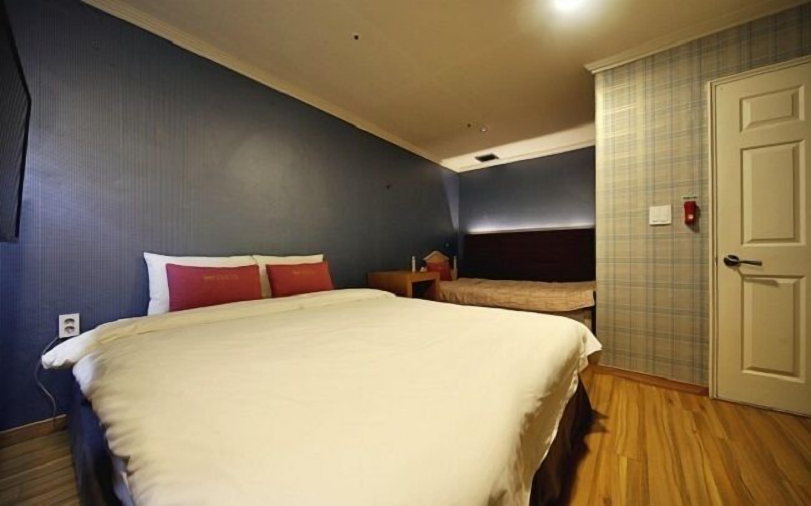 A hotel room with a large bed, a bedside table, a wardrobe, and a door.