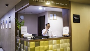 Un mostrador de recepción de hotel con un reloj, certificados enmarcados y un cartel que indica la hora del desayuno.