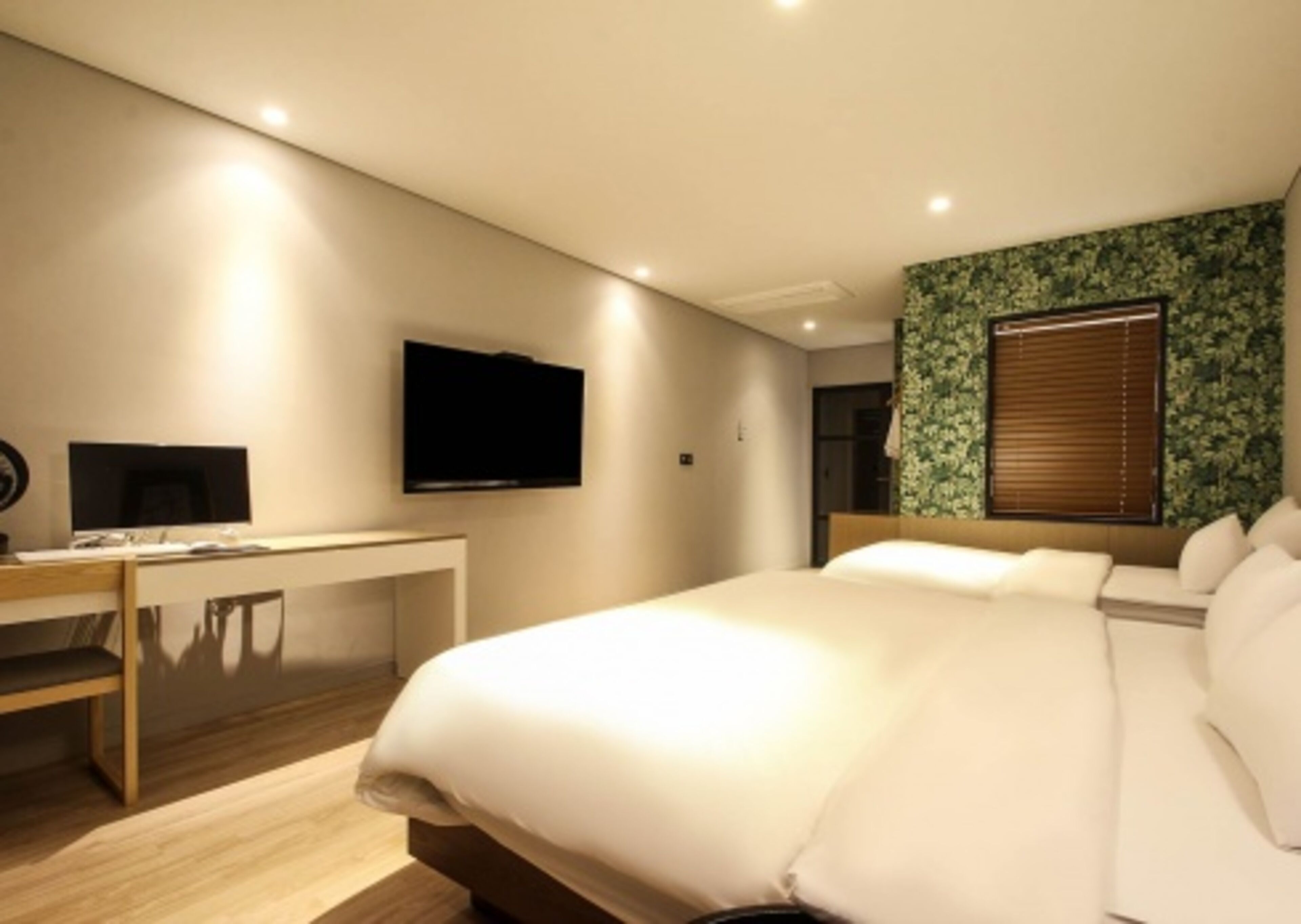 Una habitación de hotel moderna con una cama grande, un escritorio y un televisor de pantalla plana, además de un televisor montado en la pared.