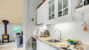 A modern kitchen with white cabinetry, a built-in stove, and a large window.