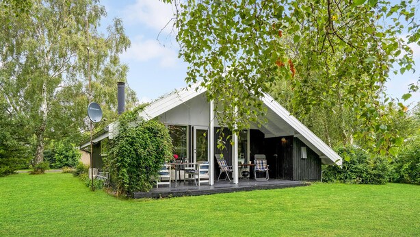 A modern house with a covered porch, a chimney, and a satellite dish.