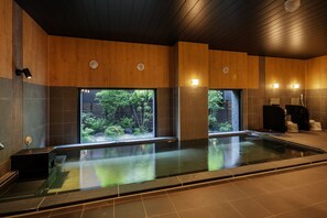 Un spa moderno con una amplia piscina interior, paredes revestidas de madera y luz natural proveniente de ventanas.