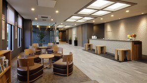 A modern reception area with a reception desk, seating area, and a large window. - Hotel Route Inn Shinano Omachi Ekimae (Omachi)