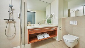 A modern bathroom with a glass-enclosed shower, a wooden vanity with a mirror, and a toilet. - Hotel Hafenspeicher - 14023 - Classic (Leer (Ostfriesland))