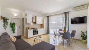Eine moderne Wohnung mit Wohnzimmer, Küche, Essbereich und einem an der Wand befestigten Fernseher.
