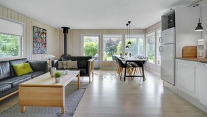 A modern kitchen with a dining area, wooden flooring, and large windows offering a view of the outdoors. - 3 bedroom amazing home in Hemmet (Hemmet)