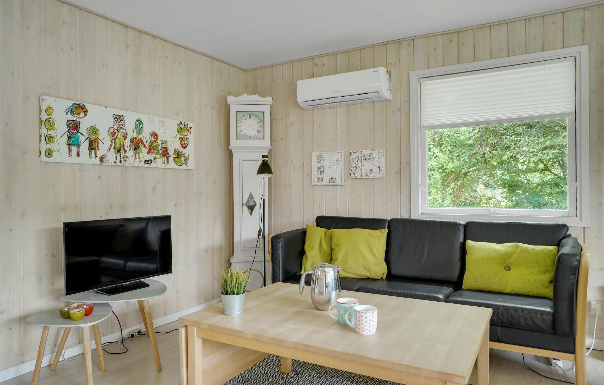 Ein Wohnzimmer mit Fernseher, Sofa, Couchtisch und Kunstwerk an der Wand.