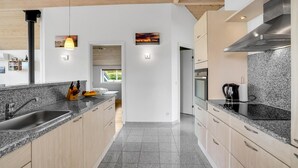 A modern kitchen with granite countertops, stainless steel appliances, and wooden cabinets. - Cozy home in Vinderup with sauna (Vinderup)