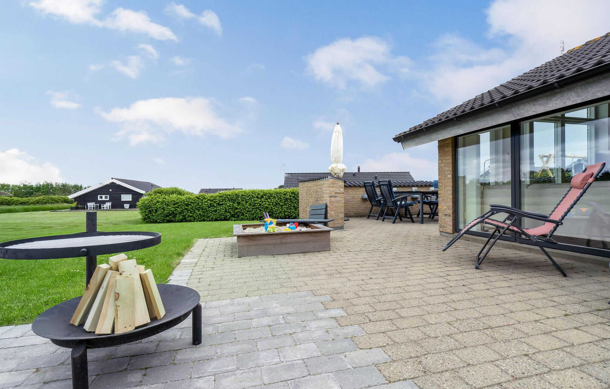 Un espace extérieur aménagé en terrasse, avec une table ronde, des chaises et un foyer.