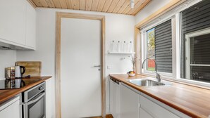 A compact kitchen with a wooden countertop, a built-in oven, a dishwasher, and a window with a view of the outside. - 2 bedroom beautiful home in Gudhjem (Gudhjem)