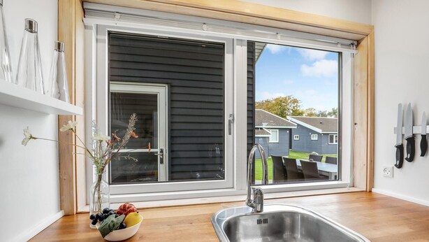 A kitchen with a large window, a sink, and a bowl of fruit on the counter. - 2 bedroom beautiful home in Gudhjem (Gudhjem)