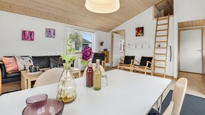 A modern living room with a white table, black leather sofa, and a wooden ceiling. - 2 bedroom beautiful home in Gudhjem (Gudhjem)