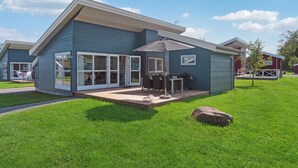 A modern two-story house with a patio, large sliding glass doors, and a covered outdoor seating area. - 2 bedroom beautiful home in Gudhjem (Gudhjem)
