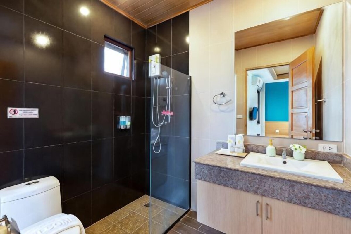 A bathroom with a shower, toilet, sink, and mirror.