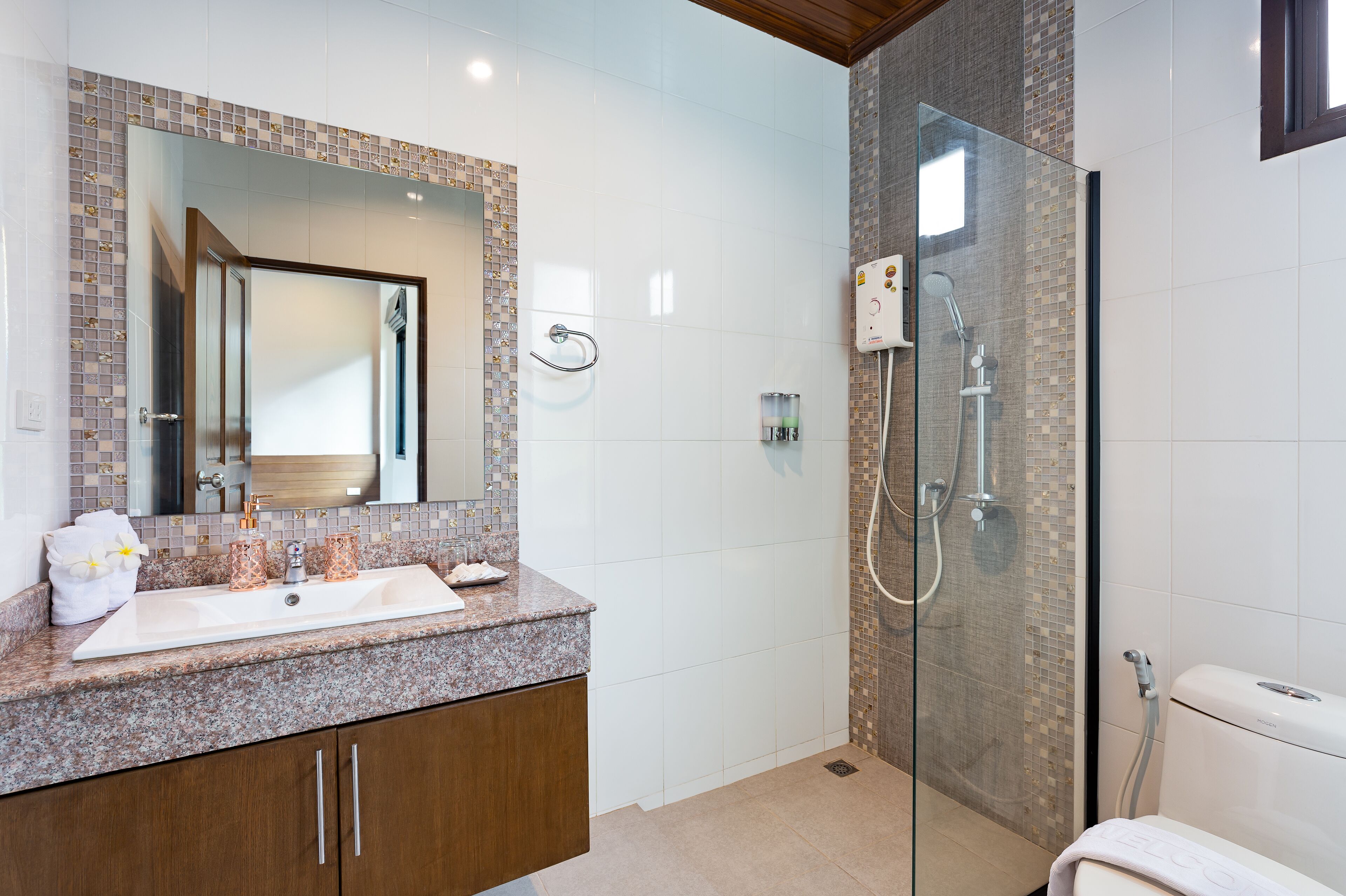 Une salle de bain moderne avec un comptoir en granit, un grand miroir, une douche à parois de verre et des toilettes.