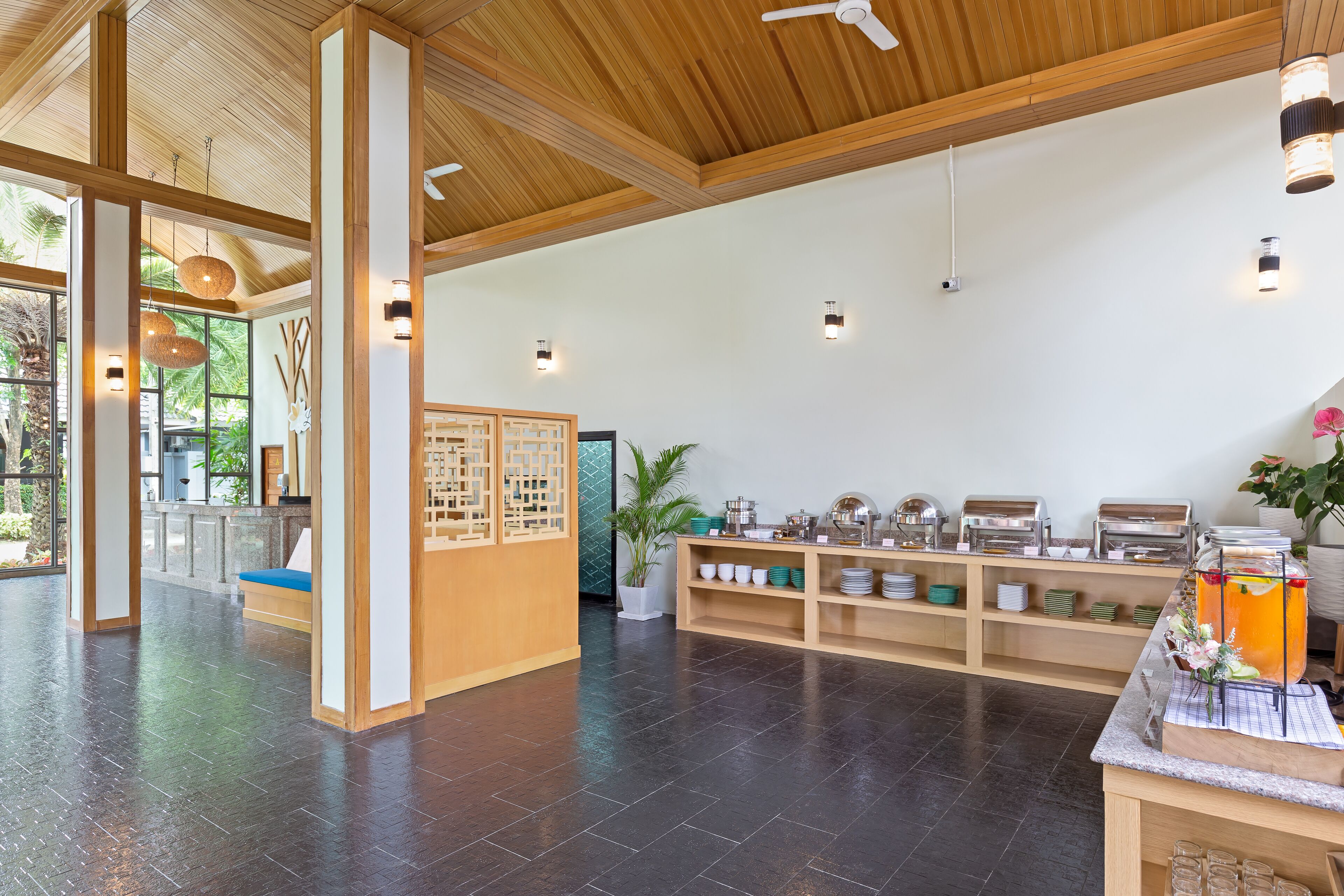 A spacious lobby with a high ceiling, wooden beams, and a buffet area with various food items and a beverage station.