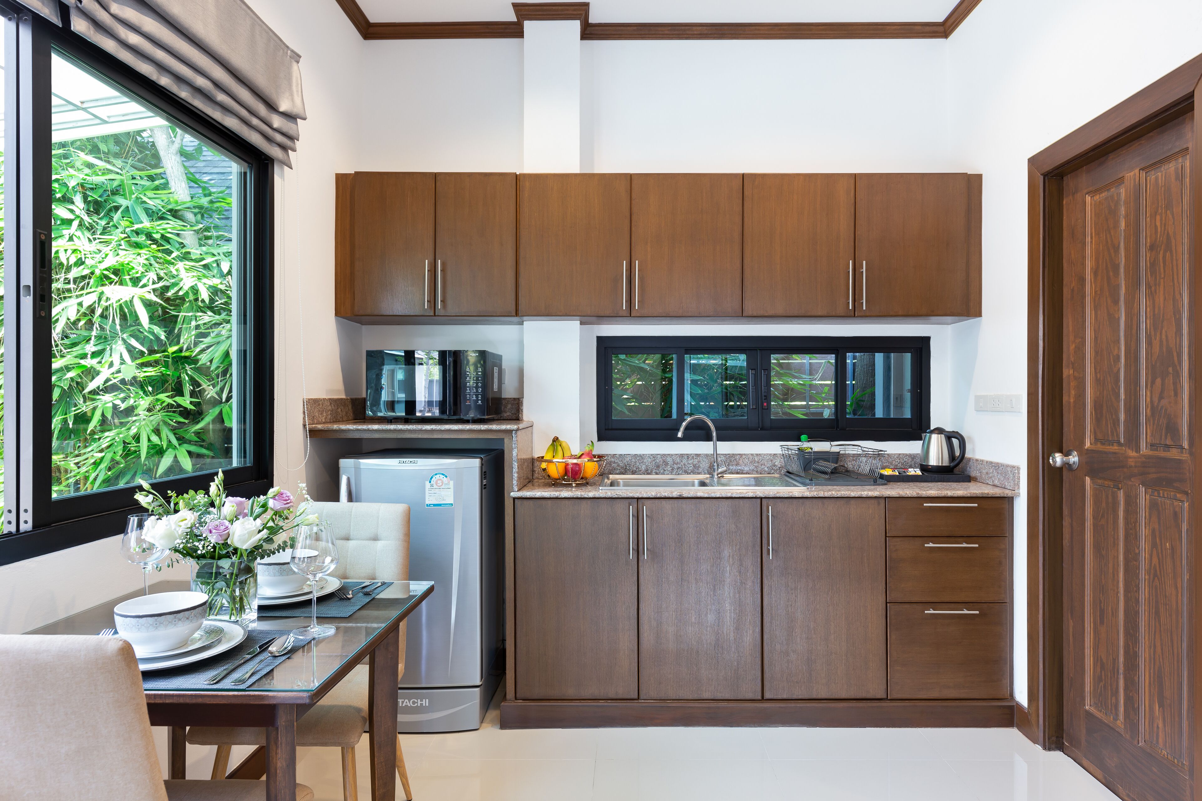 A compact kitchen with wooden cabinets, a built-in microwave, and a window overlooking greenery.