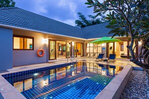 A modern house with a swimming pool, outdoor seating, and a well-lit interior. - Lady Naya Villas (Rawai)
