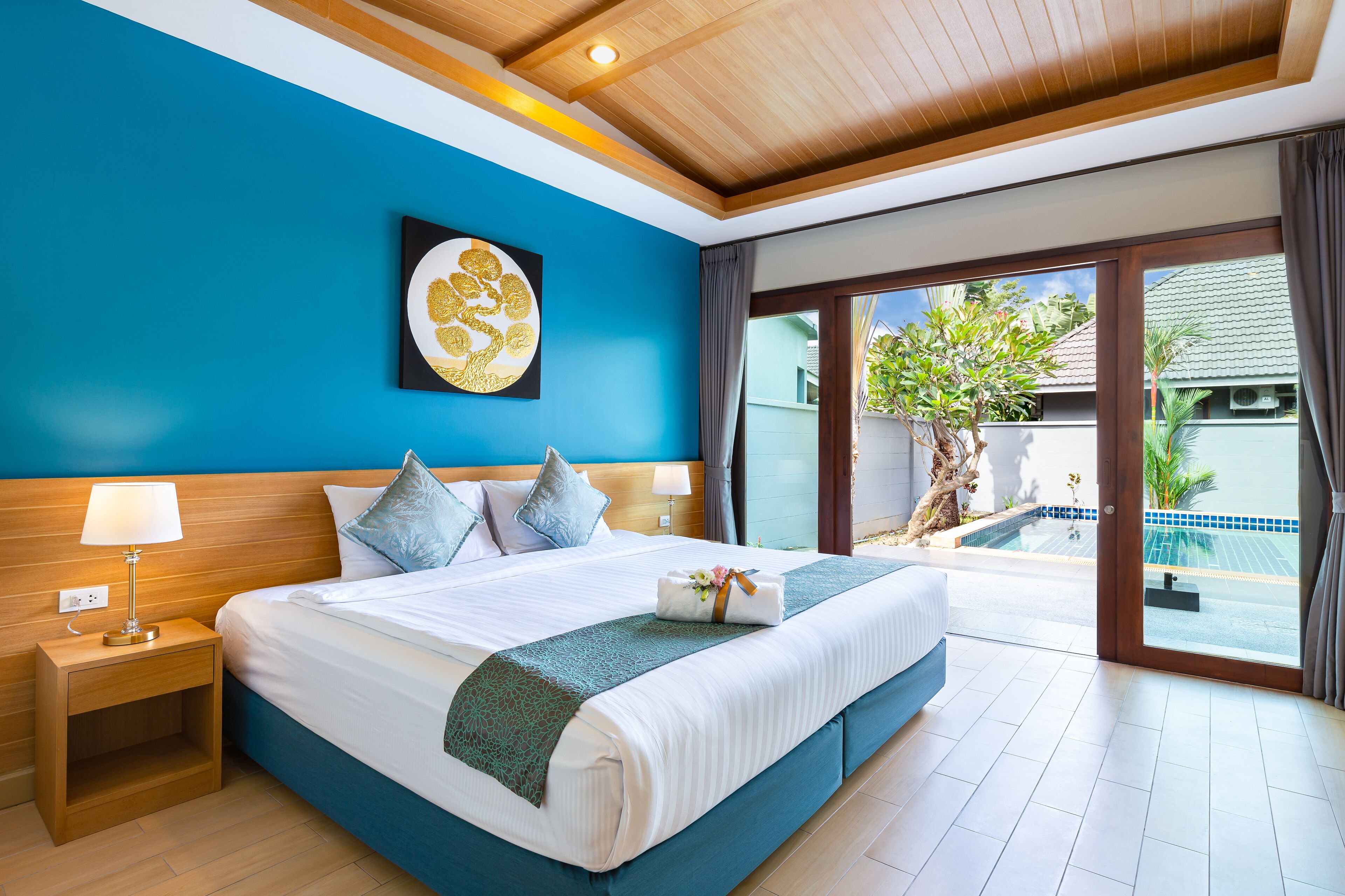 Una habitación de hotel con una cama grande, una mesita de noche, una obra de arte en la pared y vistas a una piscina.