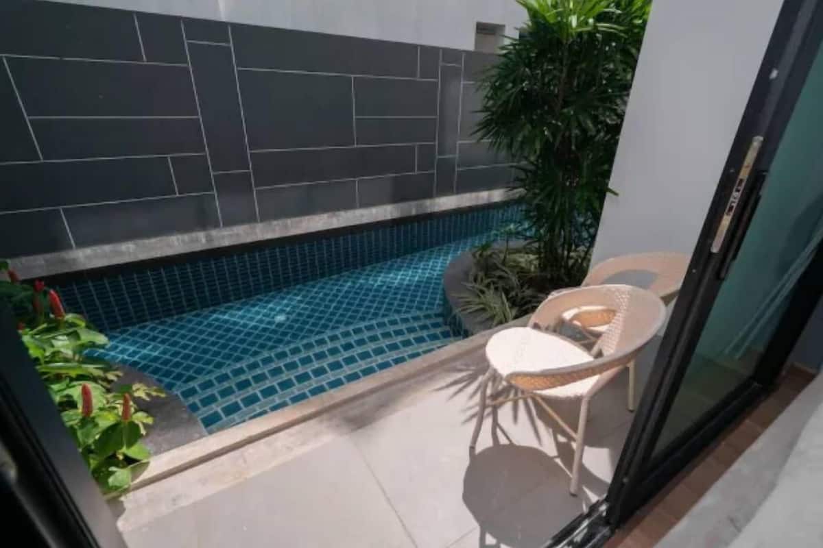 Una pequeña piscina al aire libre con suelo de baldosas, una silla y una planta en maceta.