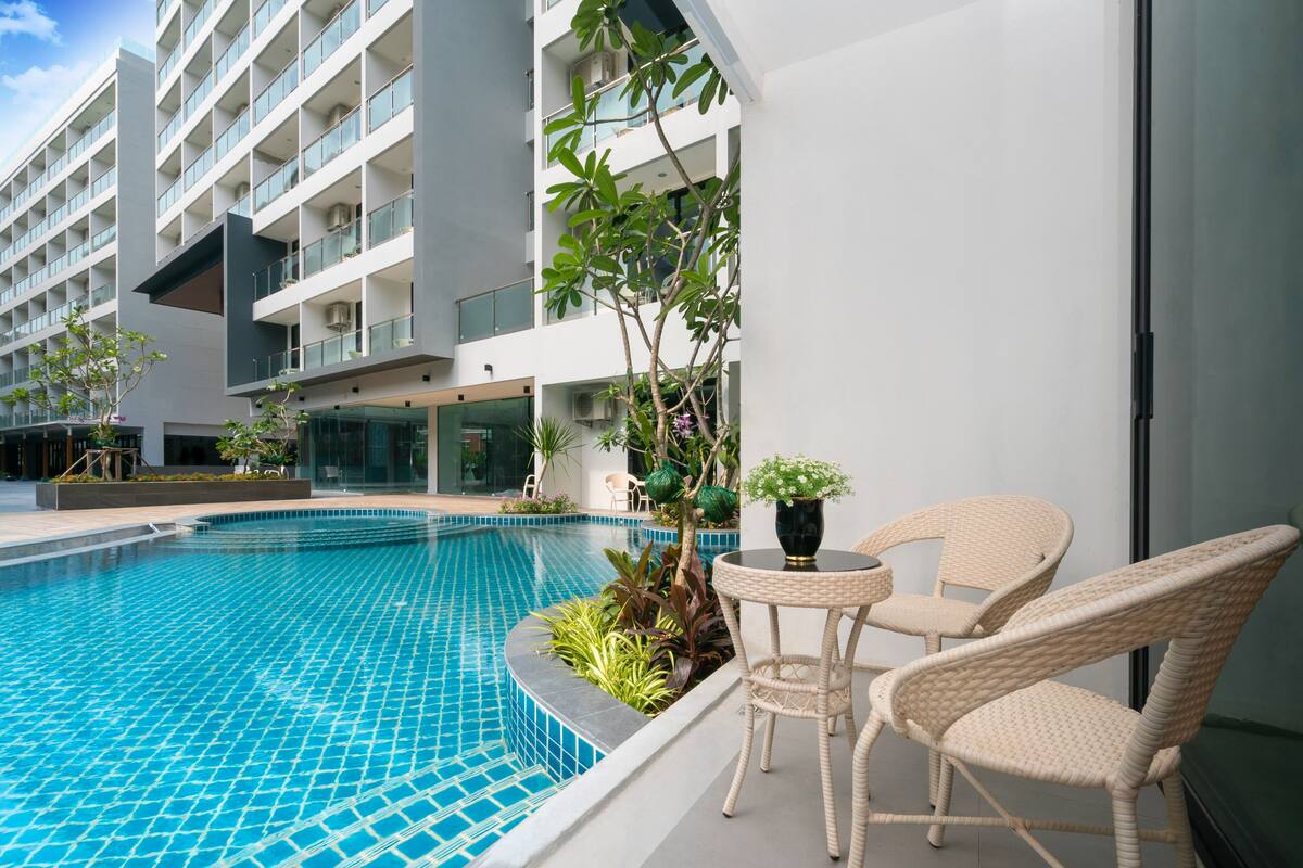 Un hotel moderno con piscina, mobiliario exterior y vistas del exterior del edificio.