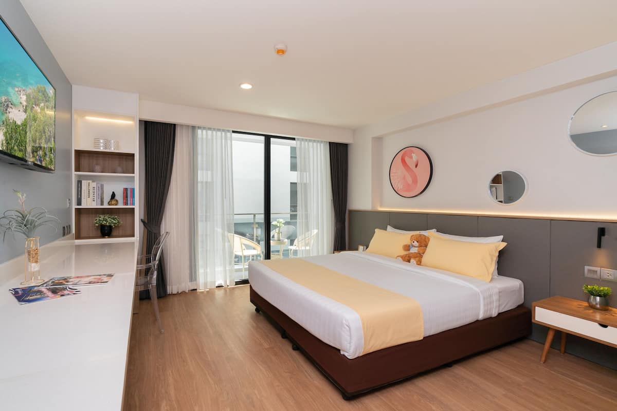 Una habitación de hotel moderna con una cama grande, un escritorio, una estantería y un balcón con vistas.