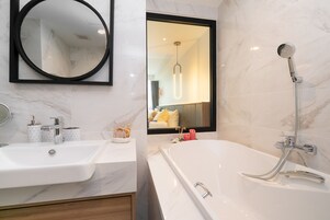Un bagno moderno con uno specchio grande, una vasca e un lavandino.