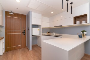 A modern kitchen with a central island, white cabinetry, and a wooden door.