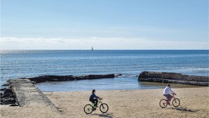 A beach with two cyclists and a sailboat in the distance. - Cozy home in Chiaramonte Gulfi (Chiaramonte Gulfi)