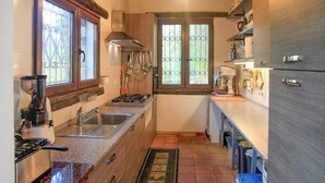 A compact kitchen with a gas stove, sink, and a window with metal bars. - Cozy home in Chiaramonte Gulfi (Chiaramonte Gulfi)