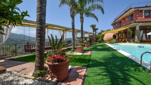 A pool area with artificial grass, palm trees, and terracotta planters. - Nice home in Laureana Cilento (Laureana Cilento)