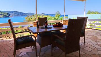 A covered patio with a table and chairs, overlooking a scenic view of a body of water and hills.